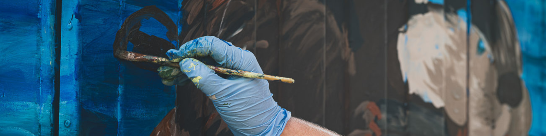 Woman painting box outside with paint brush